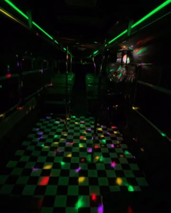 The checkerboard dance floor at night, green LED strips above and disco lights across the floor