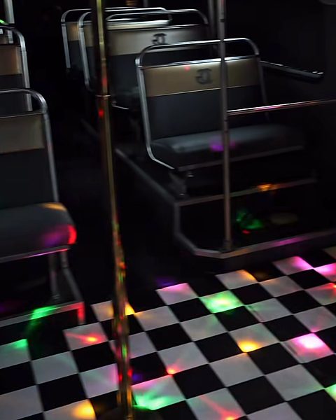 Disco lights scattered across the checkerboard floor between the seats